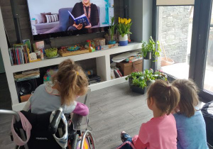 trzy siostry siedzą przed telewizorem i słuchają bajki czytanej przez lektorkę